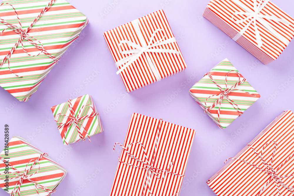 Obraz premium Many striped Christmas gift boxes on color background, top view