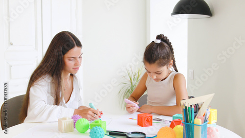 Speech therapist engages with child using colorful toys and art supplies in a bright, modern therapy space during a focused session,drawing art