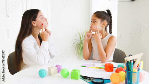 Speech therapist guides child through articulation exercises at therapy session in bright, modern office