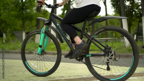 Young woman riding bicycle in park rear view 4k