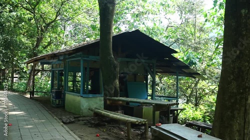 A weathered wooden structure nestled amidst lush greenery, featuring a shaded seating area.