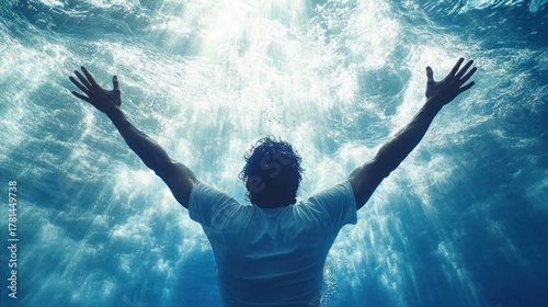 Person underwater with arms outstretched reaching towards light filtering down from the surface, creating a dramatic and uplifting scene