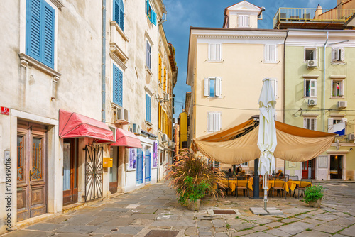 Fototapeta Naklejka Na Ścianę i Meble -  A covered sidewalk cafe in a small square of the picturesque old town district of the seaside town of Piran, Slovenia, in the Istria region along the Adriatic Sea.