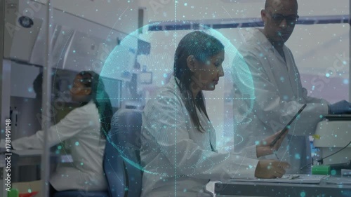 Seated scientist tapping tablet in lab, causing rotating globe over bench as team analyzing