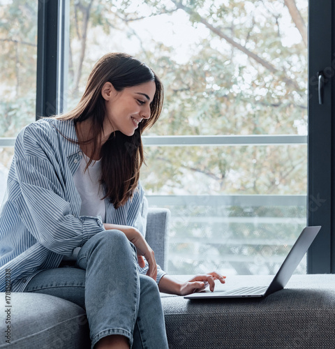 Photography Concentrated millennial girl sit on couch working on laptop browsing internet at