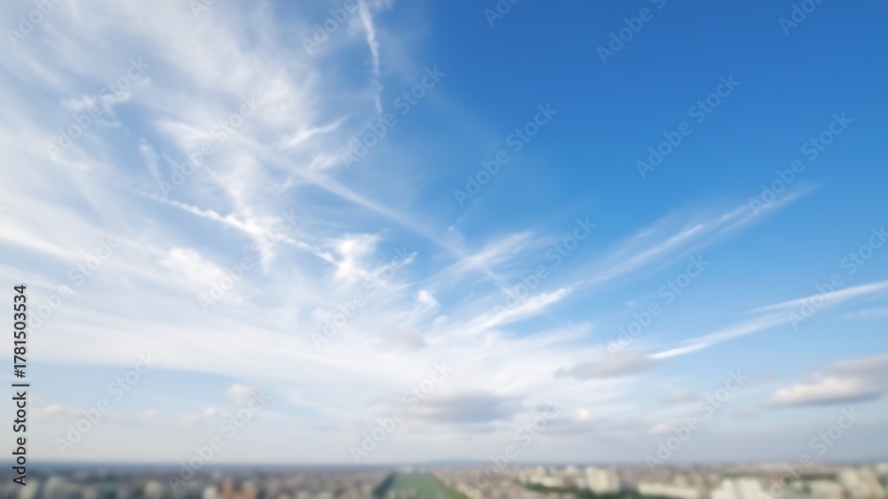 Naklejka premium Panoramic sky view with soft clouds, subtly hinting at a blurred cityscape below.