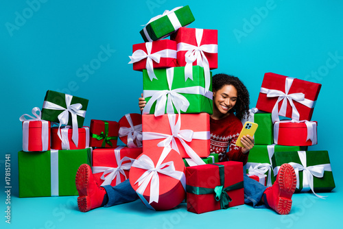Schilderij op canvas Funny cheerful girl amid a towering pile of colorful presents smiling at a brigh