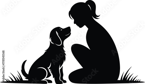 Woman kneeling in silhouette lovingly looking at a small puppy silhouette