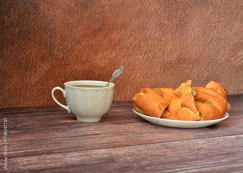 A cup of hot tea and a plate with pieces of homemade apple pie on a wooden table.