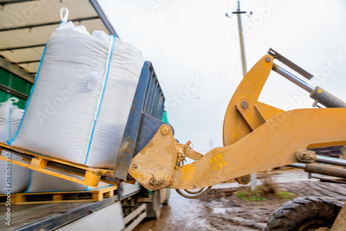 unloading of big bags with mixed feed by loader from a truck to a covered warehouse on a dairy farm