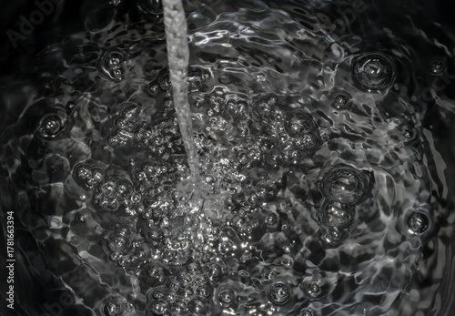 Stream of Water Splashing and Creating Ripples and Bubbles in a Container