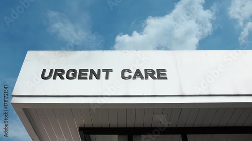 Urgent Care word sign displayed on a medical clinic building under a clear blue sky, symbolizing immediate healthcare, walk-in services, medical assistance, non-emergency treatment, and accessible