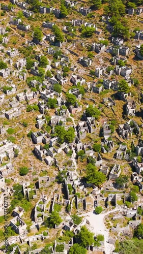 Vertical video. Kayakoy, Turkey. Aerial drone view of abandoned ghost town ruins and stone houses on mountain slopes under clear blue sky.. Aerial View, MasterShots, Rocket. Rich colors