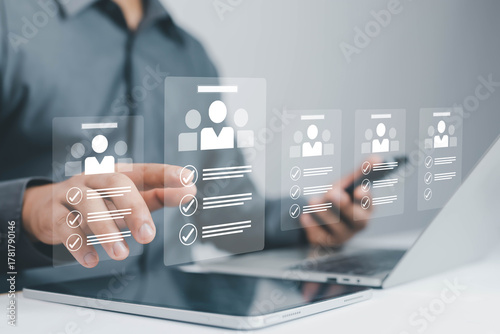 Tableau sur toile Businessman using laptop with virtual interface for online recruitment and human resources management, selecting candidate profiles