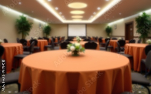 Blurred background of an elegant conference room featuring round tables with orange tablecloths and modern decor for professional gatherings. High quality