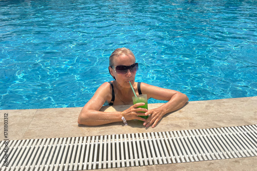 A retired woman enjoys a cold lemonade in the pool