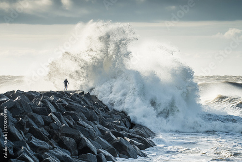 Fototapeta Naklejka Na Ścianę i Meble -  surfer riding massive wave as it crashes against rocky breakwater