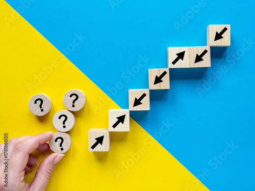 Hand placing question mark blocks and cubes with arrows forming a staircase on a blue and yellow background