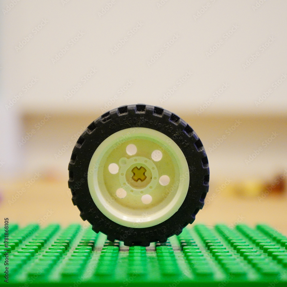 Fototapeta premium Lego wheel on a green baseplate, a classic toy for creative building