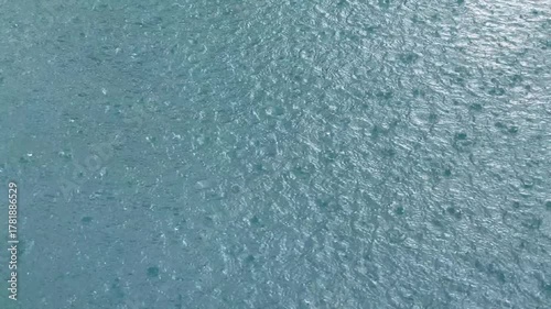 Raindrops fall on the blue water surface background