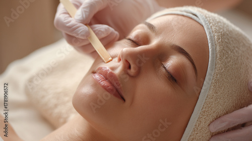 Close up of woman receiving facial waxing treatment at a beauty salon spa