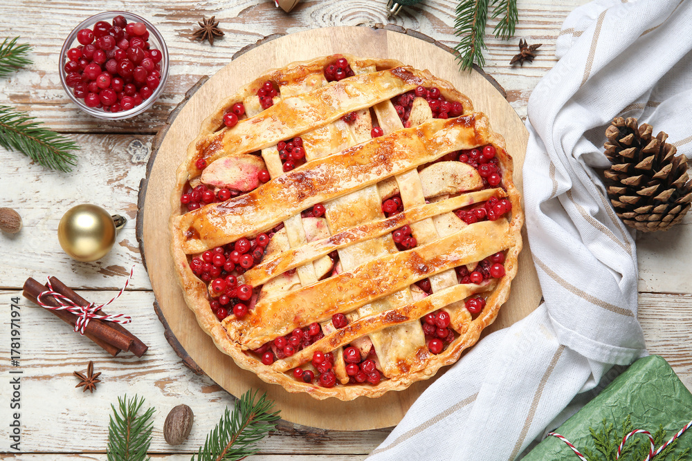 Obraz premium Tasty cranberry pie with cinnamon and Christmas tree branches on white wooden background