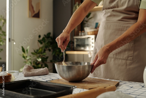 Fotografia Caucasian young adult woman mixing ingredients in metal bowl with whisk on kitch
