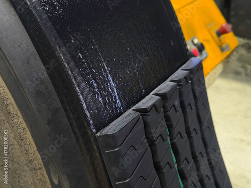 At the tire retreading factory, the master applies the bonding gum that connects the cold tread to the tire.