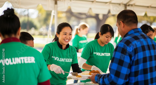 Group of volunteers serving food. They wear green shirts marked 