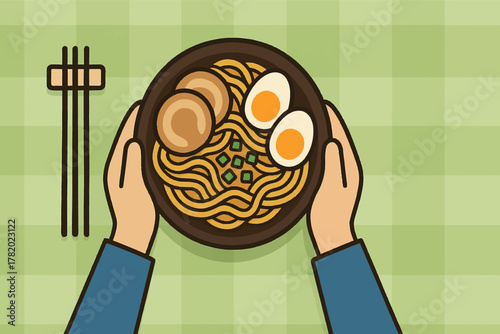 Overhead view of hands holding a bowl of ramen with eggs and pork on a green checkered tablecloth