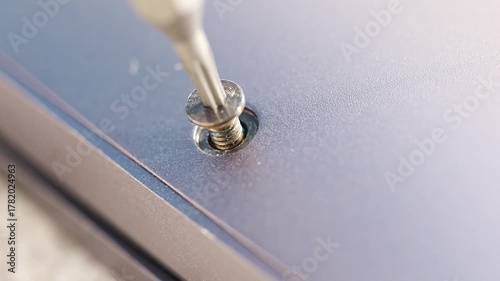close up. screwdriver and screw. A technician disassembles a laptop.