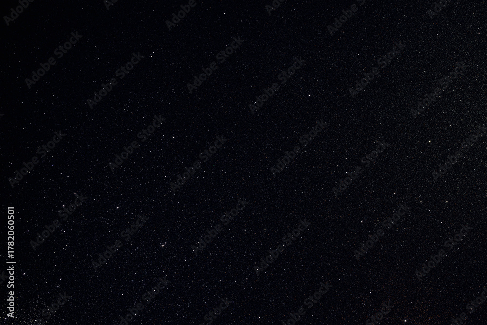 Fototapeta premium Dark granular surface enriched with glitter and golden inclusions, sharp macro focus highlights rare spark points