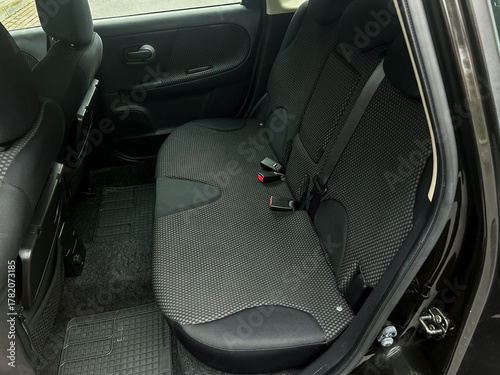 Backseat of a compact car showcases spacious yet cozy seating for three passengers during a rainy day outing in the city