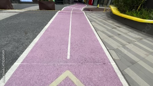 紫色の歩道と矢印マークが並ぶモダンな都市デザインの映像