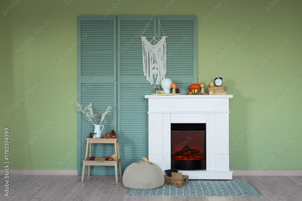 Obraz premium Modern living room with fireplace, coffee table, alarm clock and pumpkins. Autumn concept