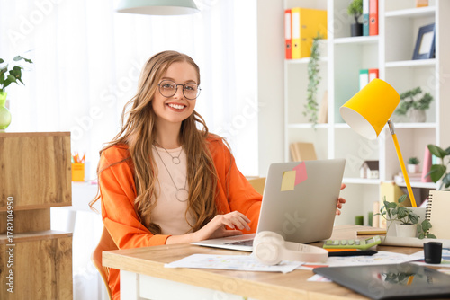 Female web designer working with laptop at table in office