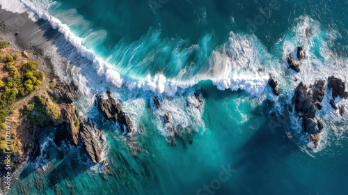 Fototapeta Naklejka Na Ścianę i Meble -  Majestic aerial view of dynamic ocean wave crashing on rugged coastline with rock. Beautiful scenic nature landscape from above for travel