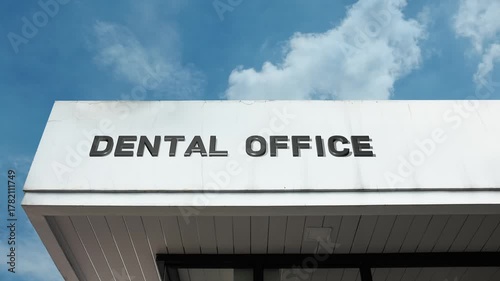 Dental Office word sign displayed on a commercial or medical building under a clear blue sky, symbolizing oral health, dentistry, medical services, hygiene, patient care, and professional treatment