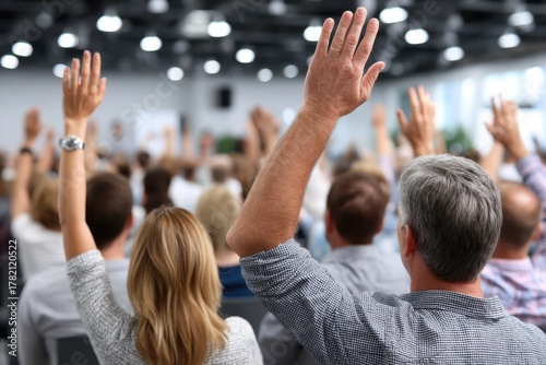 Participants engage in discussion by raising hands during a conference in a modern venue
