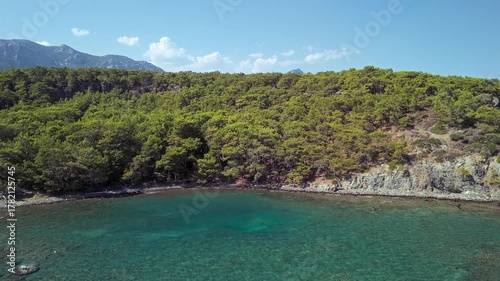 Drone view of Phaselis Bay with turquoise water, pine forest, and Mount Olympos in the background. Beautiful Mediterranean landscape near Kemer, Antalya, Turkey.