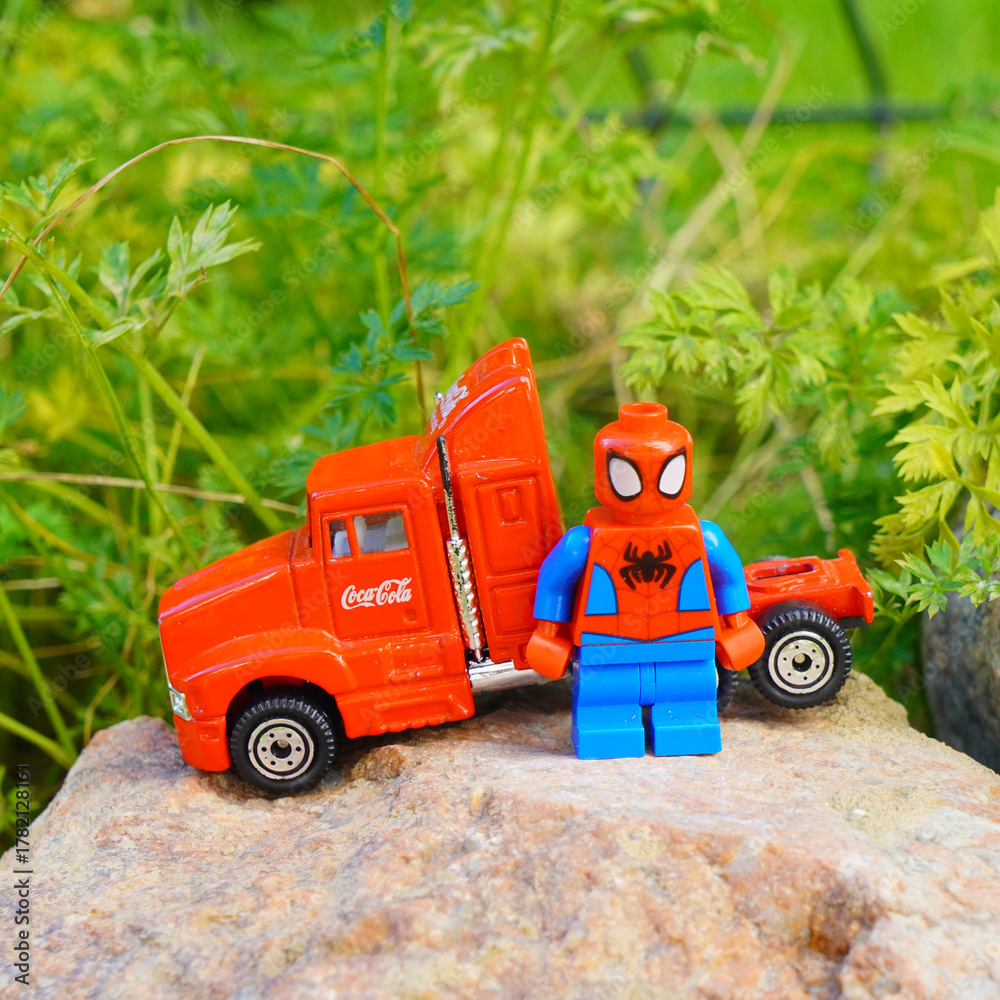 Naklejka premium Spider-Man Lego figure stands next to a Coca-Cola truck on a rock