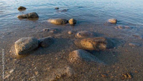 Gently illuminated river rocks spread along the water's edge at twilight