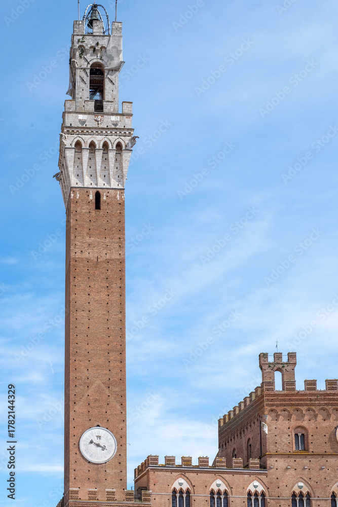 Obraz premium Siena cathedral tower rises majestically against a clear blue sky, showcasing intricate architectural details and ancient brickwork, inviting exploration and admiration of historical beauty