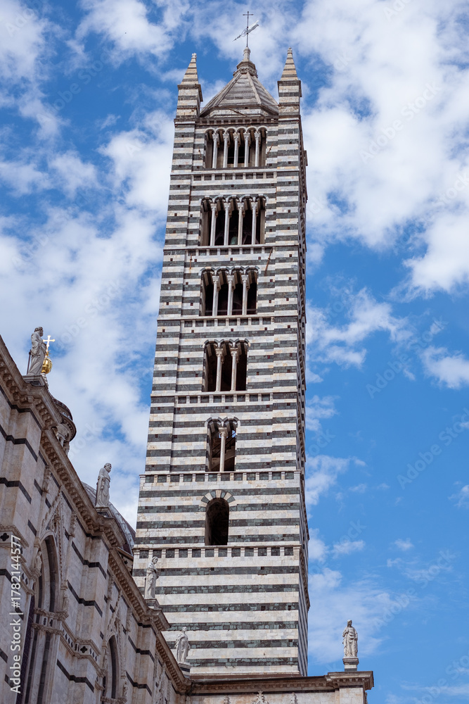 Obraz premium Striking bell tower In Siena, Italy with intricate stonework rises against a vibrant blue sky, showcasing architectural beauty and historical significance in a captivating sightseeing destination