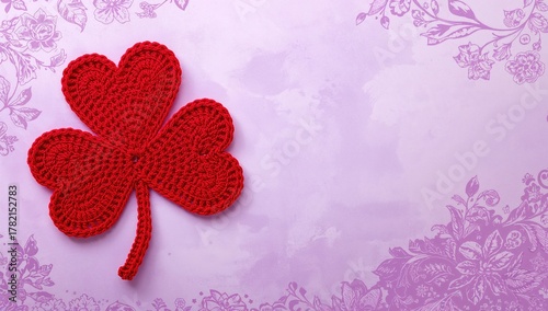 A St. Patrick's Day themed display of red crocheted hearts shaped like a four-leaf clover on a lilac background, festive decoration