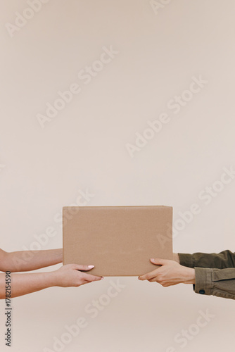 Hands Transferring Cardboard Box Between Two Persons