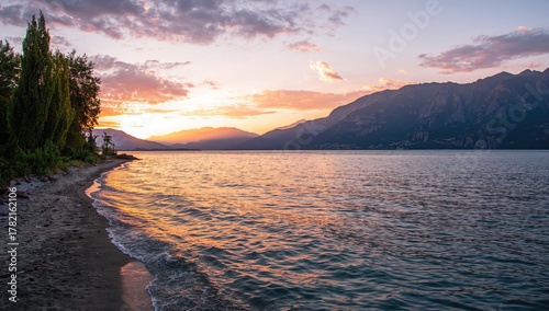 Fototapeta Naklejka Na Ścianę i Meble -  Evening Glow Over a Serene Lake with Beach and Mountains