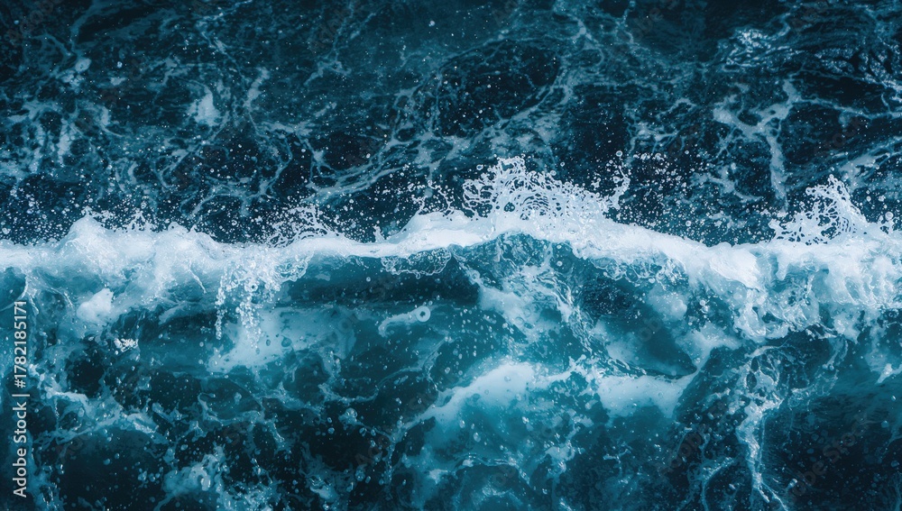 Fototapeta premium Ocean surface displaying waves, foamy splashes, and bubbles amid high surf against a blue abstract background.