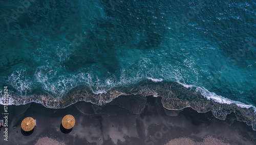 Fototapeta Naklejka Na Ścianę i Meble -  Aerial view of black sand beach with turquoise waters and straw umbrellas, ideal for vacation travel