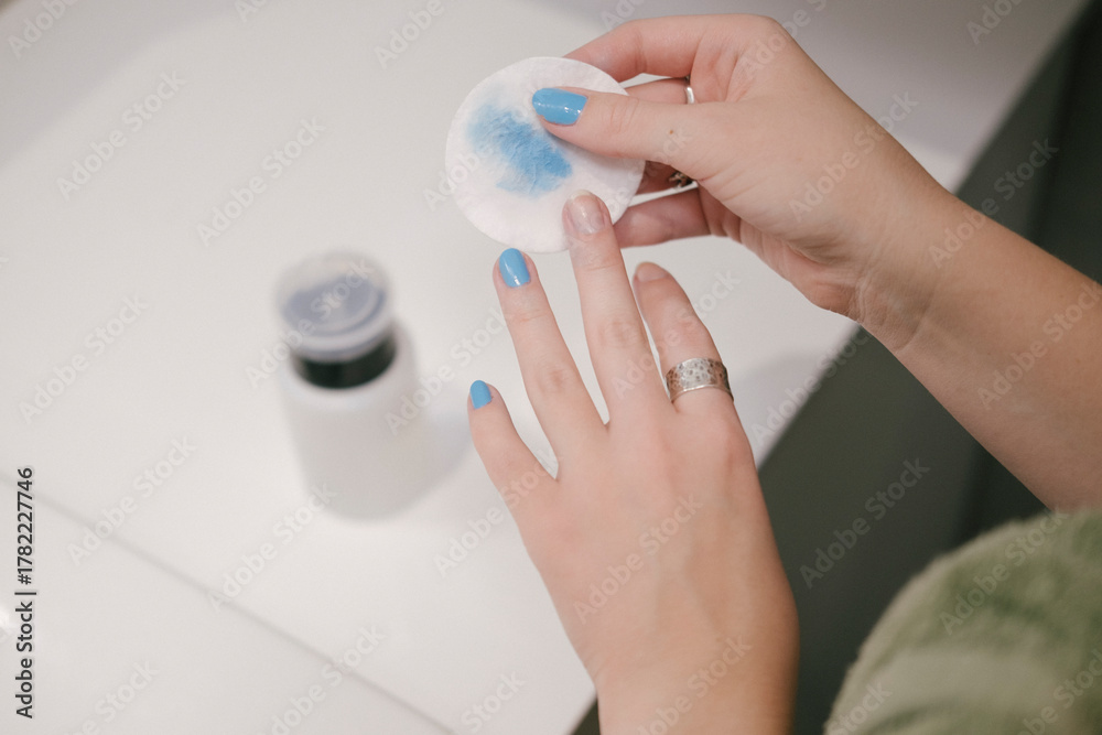 Φωτογραφία Manicure scene with hands and cleansing pad applying product to nails, nail care routine in soft lighting, beauty and personal care setup with a polish bottle nearby